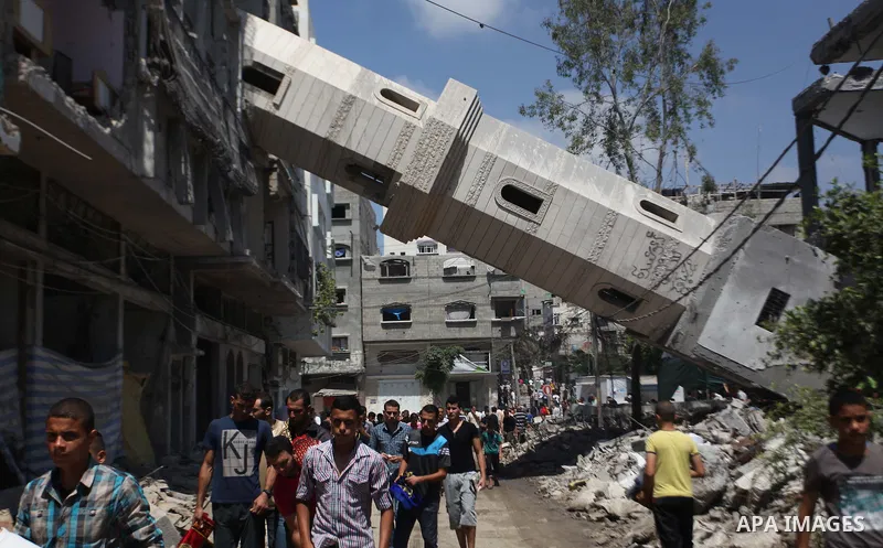 A collapsed minaret is seen as Palestinians leave after performing Friday prayers at the remains of a mosque, which witnesses said was hit by an Israeli air strike during a seven-week Israeli offensive in Gaza City Augus...