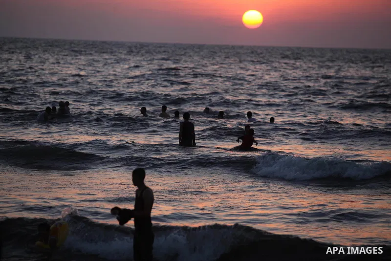 Palestinians swim in the Mediterranean Sea off the coast of Gaza City during sunset August 29, 2014, days after a ceasefire was reached. An open-ended ceasefire, mediated by Egypt, took effect on Tuesday evening. It call...