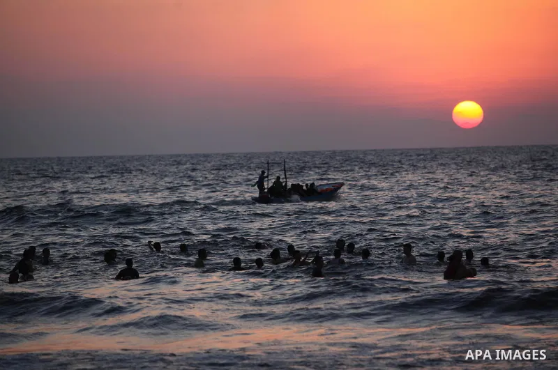 Palestinians swim in the Mediterranean Sea off the coast of Gaza City during sunset August 29, 2014, days after a ceasefire was reached. An open-ended ceasefire, mediated by Egypt, took effect on Tuesday evening. It call...