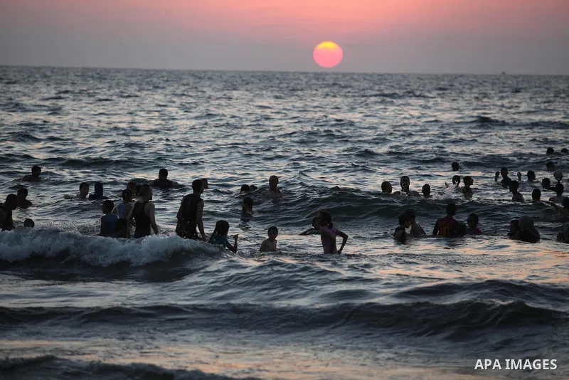 Palestinians swim in the Mediterranean Sea off the coast of Gaza City during sunset August 29, 2014, days after a ceasefire was reached. An open-ended ceasefire, mediated by Egypt, took effect on Tuesday evening. It call...
