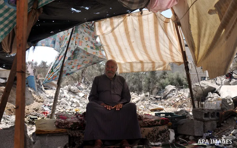 A Palestinian man sits at a tent on a the rubble of his house which witnesses said was destroyed during the Israeli offensive in Shejaiya neighborhood after a ceasefire was declared, in Gaza city on August 30, 2014. An o...