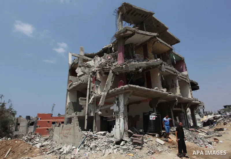 Palestinians walk past buildings destroyed during fighting between Hamas militants and Israel in the Al-Shaaf neighbourhood, in Gaza City, on August 31, 2014. An indefinite ceasefire to end seven weeks of fighting betwee...
