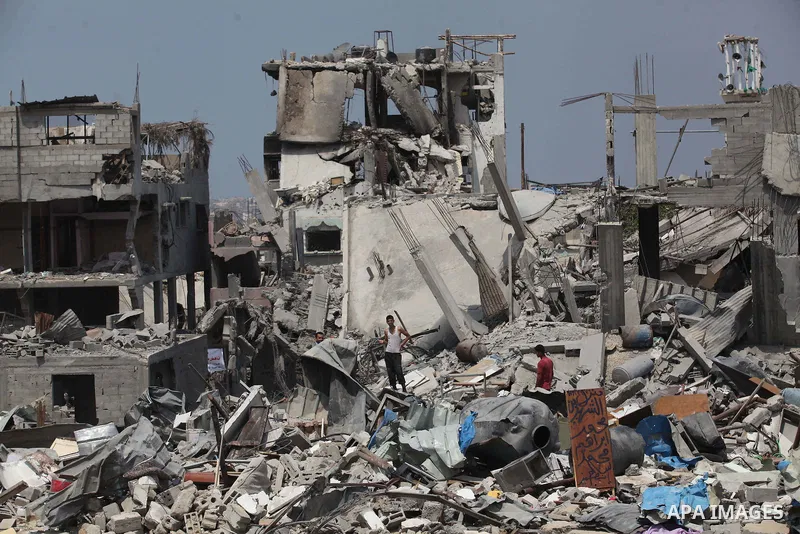 Palestinians walk past buildings destroyed during fighting between Hamas militants and Israel in the Al-Shaaf neighbourhood, in Gaza City, on August 31, 2014. An indefinite ceasefire to end seven weeks of fighting betwee...