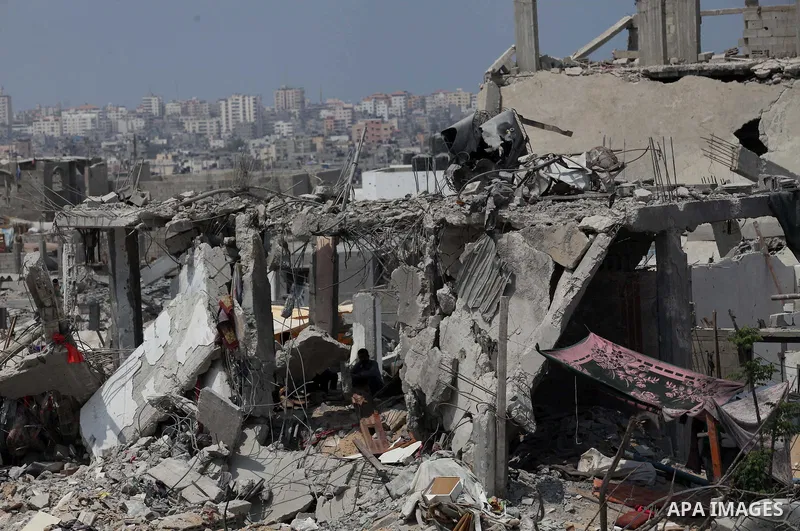 Palestinians walk past buildings destroyed during fighting between Hamas militants and Israel in the Al-Shaaf neighbourhood, in Gaza City, on August 31, 2014. An indefinite ceasefire to end seven weeks of fighting betwee...