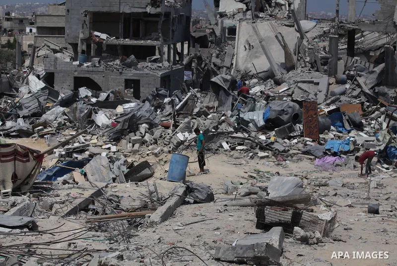 Palestinians walk past buildings destroyed during fighting between Hamas militants and Israel in the Al-Shaaf neighbourhood, in Gaza City, on August 31, 2014. An indefinite ceasefire to end seven weeks of fighting betwee...