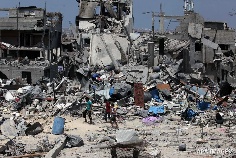 Palestinians walk past buildings destroyed during fighting between Hamas militants and Israel in the Al-Shaaf neighbourhood, in Gaza City, on August 31, 2014. An indefinite ceasefire to end seven weeks of fighting betwee...