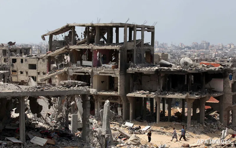 Palestinians walk past buildings destroyed during fighting between Hamas militants and Israel in the Al-Shaaf neighbourhood, in Gaza City, on August 31, 2014. An indefinite ceasefire to end seven weeks of fighting betwee...