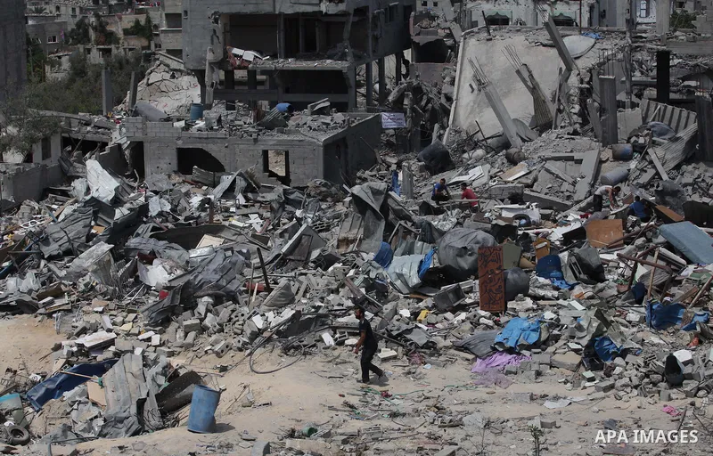 Palestinians walk past buildings destroyed during fighting between Hamas militants and Israel in the Al-Shaaf neighbourhood, in Gaza City, on August 31, 2014. An indefinite ceasefire to end seven weeks of fighting betwee...
