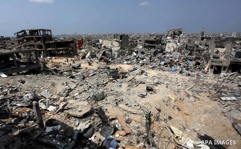 Palestinians walk past buildings destroyed during fighting between Hamas militants and Israel in the Al-Shaaf neighbourhood, in Gaza City, on August 31, 2014. An indefinite ceasefire to end seven weeks of fighting betwee...