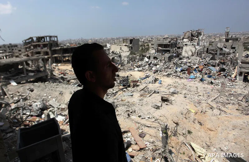A Palestinian man stands past buildings destroyed during fighting between Hamas militants and Israel in the Al-Shaaf neighbourhood, in Gaza City, on August 31, 2014. An indefinite ceasefire to end seven weeks of fighting...