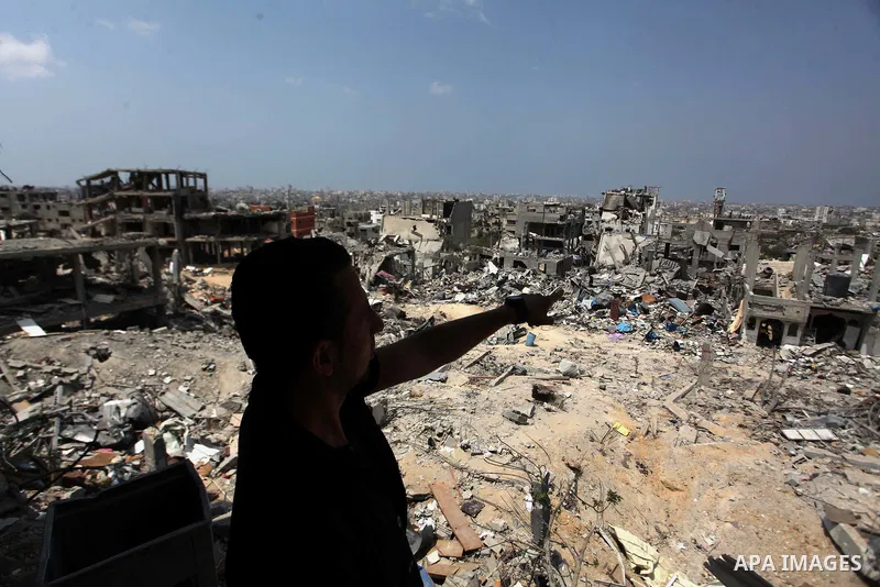 A Palestinian man stands past buildings destroyed during fighting between Hamas militants and Israel in the Al-Shaaf neighbourhood, in Gaza City, on August 31, 2014. An indefinite ceasefire to end seven weeks of fighting...