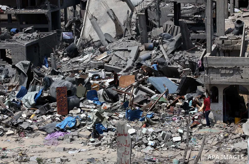 Palestinians walk past buildings destroyed during fighting between Hamas militants and Israel in the Al-Shaaf neighbourhood, in Gaza City, on August 31, 2014. An indefinite ceasefire to end seven weeks of fighting betwee...