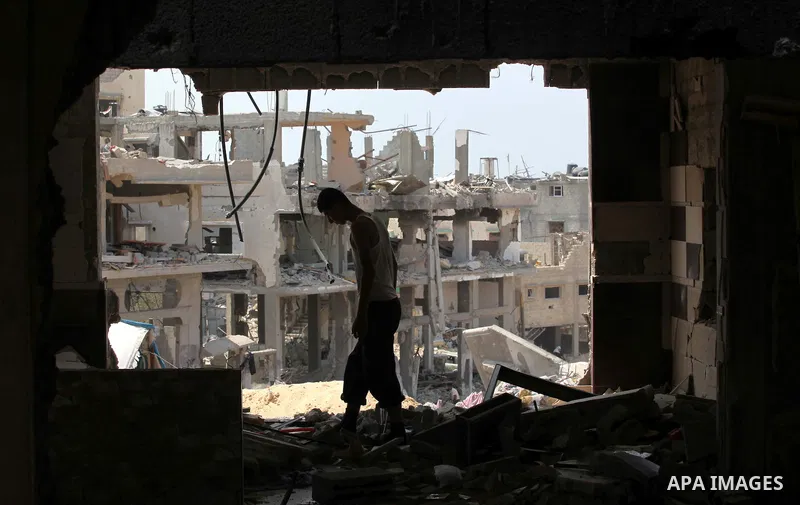 A Palestinian man walks past buildings destroyed during fighting between Hamas militants and Israel in the Al-Shaaf neighbourhood, in Gaza City, on August 31, 2014. An indefinite ceasefire to end seven weeks of fighting...