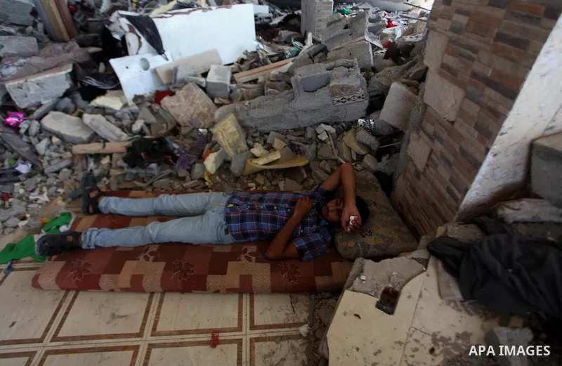 Palestinians sit on a sofa at their house which destroyed during fighting between Hamas militants and Israel in the Al-Shaaf neighbourhood, in Gaza City, on August 31, 2014. An indefinite ceasefire to end seven weeks of...