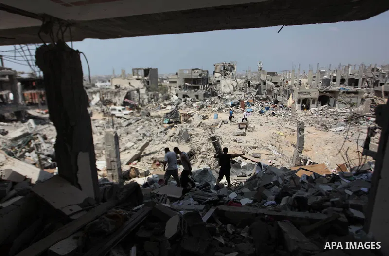 Palestinians walk past buildings destroyed during fighting between Hamas militants and Israel in the Al-Shaaf neighbourhood, in Gaza City, on August 31, 2014. An indefinite ceasefire to end seven weeks of fighting betwee...