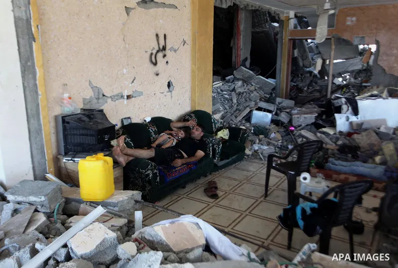 Palestinians sit on a sofa at their house which destroyed during fighting between Hamas militants and Israel in the Al-Shaaf neighbourhood, in Gaza City, on August 31, 2014. An indefinite ceasefire to end seven weeks of...
