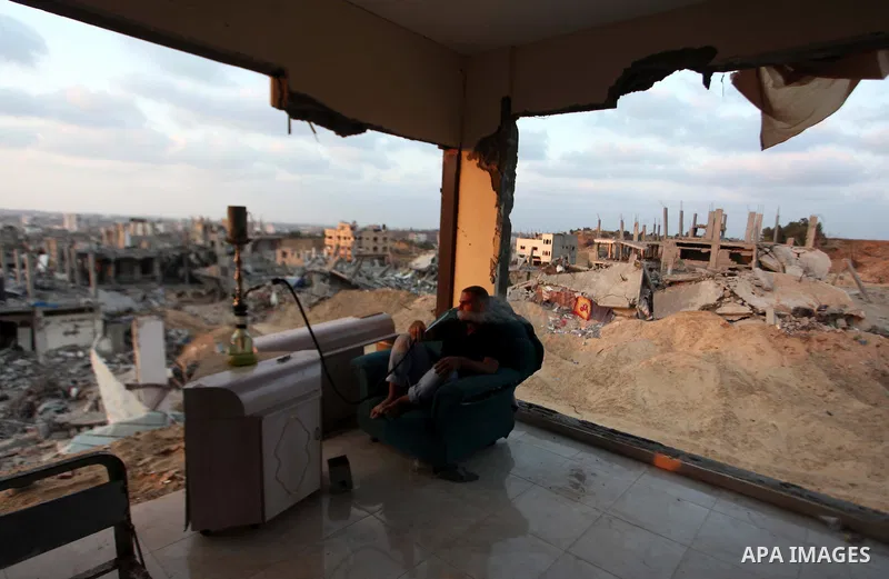 A Palestinian man smokes flavoured tobacco water pipes or 'shisha' inside his destroyed house after returning home in the Tufah neighbourhood in eastern Gaza City on August 31, 2014. Calm returned to the coastal enclave...