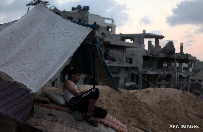 A palestinian man sits under a tent among a destroyed house after returning home in the Tufah neighbourhood in eastern Gaza City on August 31, 2014. Calm returned to the coastal enclave in a August 26 ceasefire, and Gaza...