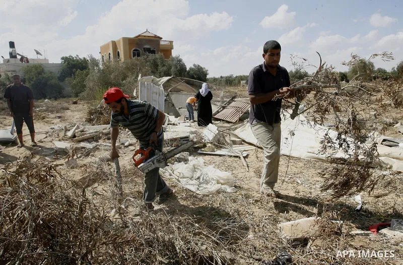 Palestinians inspect their farmland which destroyed during fighting between Hamas militants and Israel near the Israeli Gaza border fence in east of Khan Younis, southern Gaza Strip September 2, 2014. An open-ended cease...