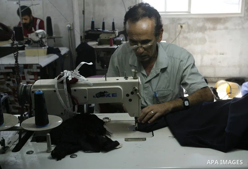 A Palestinian man tailor sews clothes at a workshop in Rafah in the southern Gaza Strip, on Sep. 04, 2014. Calm returned to the coastal enclave in a August 26 ceasefire, and Gazans were gradually starting to rebuild thei...