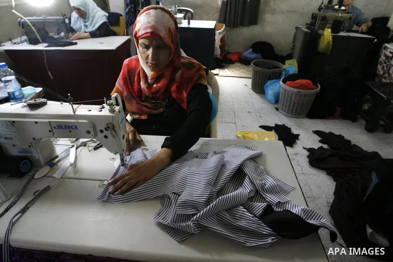 A Palestinian woman tailor sews clothes at a workshop in Rafah in the southern Gaza Strip, on Sep. 04, 2014. Calm returned to the coastal enclave in a August 26 ceasefire, and Gazans were gradually starting to rebuild th...