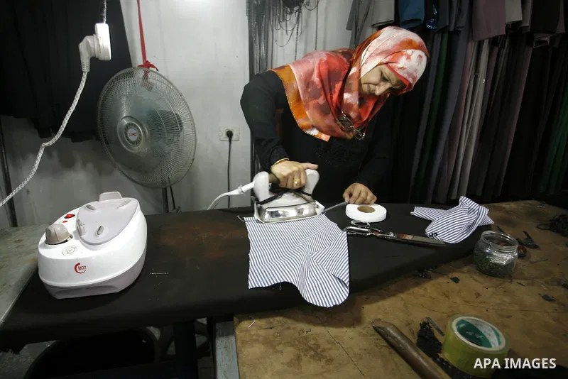 A Palestinian woman tailor sews clothes at a workshop in Rafah in the southern Gaza Strip, on Sep. 04, 2014. Calm returned to the coastal enclave in a August 26 ceasefire, and Gazans were gradually starting to rebuild th...