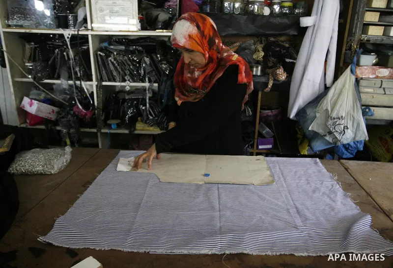 A Palestinian woman tailor sews clothes at a workshop in Rafah in the southern Gaza Strip, on Sep. 04, 2014. Calm returned to the coastal enclave in a August 26 ceasefire, and Gazans were gradually starting to rebuild th...