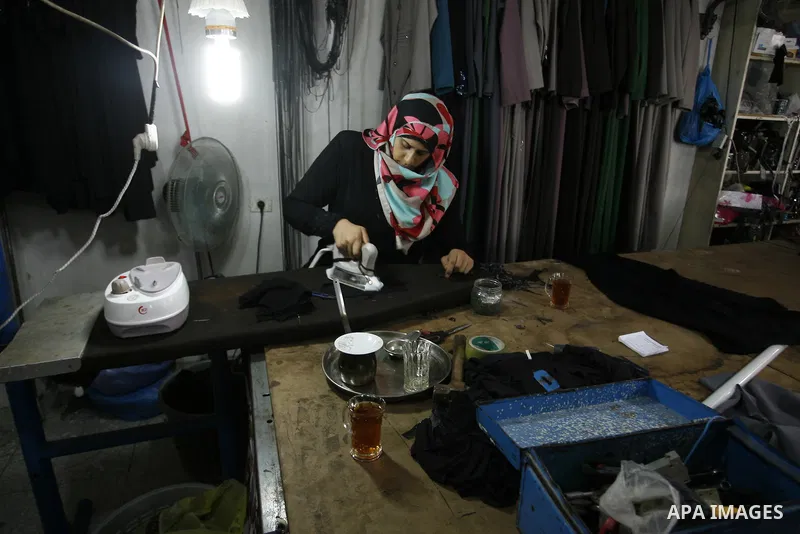 A Palestinian woman tailor sews clothes at a workshop in Rafah in the southern Gaza Strip, on Sep. 04, 2014. Calm returned to the coastal enclave in a August 26 ceasefire, and Gazans were gradually starting to rebuild th...