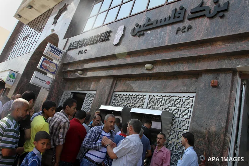 Palestinian employees paid by the Palestinian Authority wait to receive their salaries from an ATM, outside a Bank in Gaza City Sep. 07, 2014. Many issues involving the Strip, such as the fate of former employees of the...
