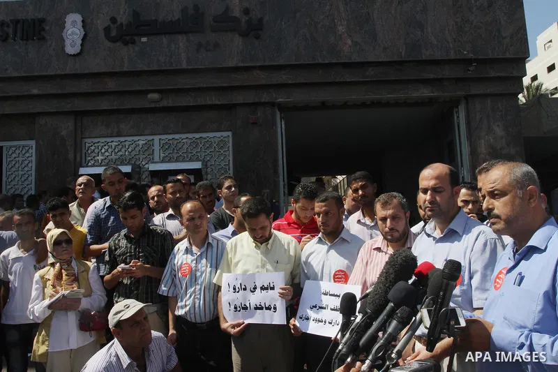 Former head of the union staff in Gaza, Mohammed Siam speaks during a press conference as Palestinian employees of the former government in Gaza Strip hold placards during a protest against not receiving their salaries,...