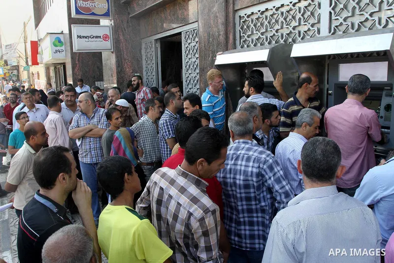 Palestinian employees paid by the Palestinian Authority wait to receive their salaries from an ATM, outside a Bank in Gaza City Sep. 07, 2014. Many issues involving the Strip, such as the fate of former employees of the...