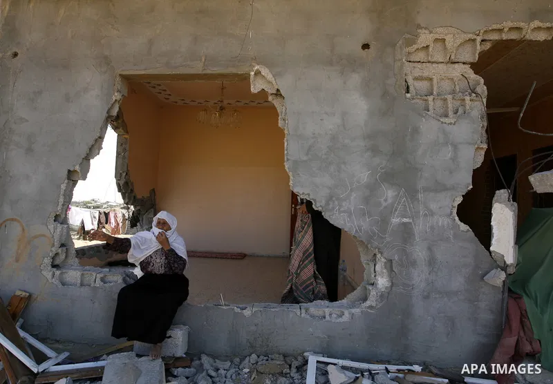 A Palestinian woman sits on the rubble of her house which destroyed during fighting between Hamas militants and Israel in east of Rafah in southern Gaza strip on September 07, 2014. Calm returned to the coastal enclave i...