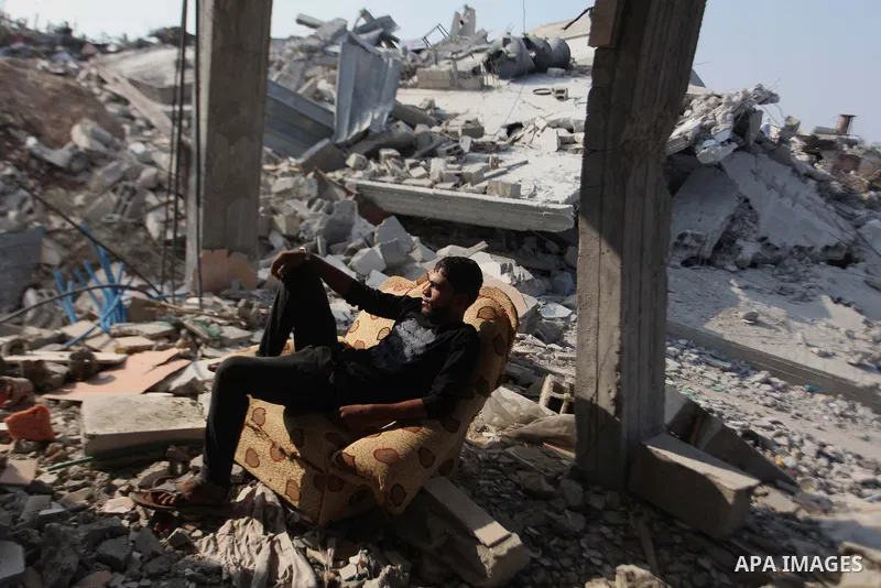 A Palestinian man sits on a sofa on the rubble of his house which destroyed during fighting between Hamas militants and Israel in the center of Gaza strip on September 08, 2014. Calm returned to the coastal enclave in a...