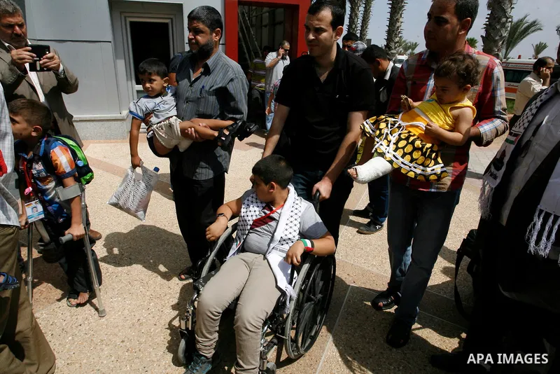 A Palestinian man carries his child, who medics said was wounded during the Israeli offensive on Gaza Strip, waits to be given the permission to cross into Egypt at the Rafah border crossing in the southern Gaza Strip, o...