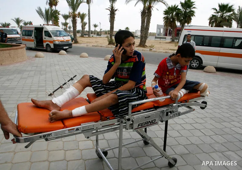 A Palestinian medic wheels a wounded on a stretche child who medics said was wounded during the Israeli offensive on Gaza Strip, waits to be given the permission to cross into Egypt at the Rafah border crossing in the so...