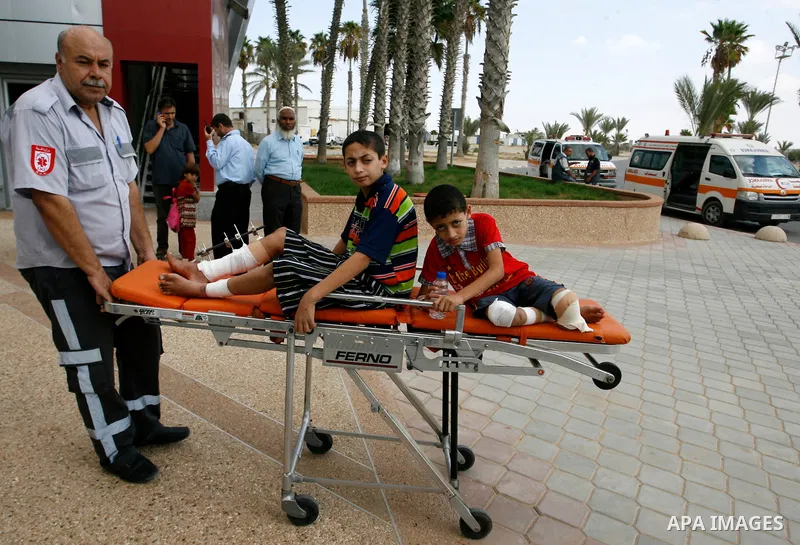 A Palestinian medic wheels a wounded on a stretche child who medics said was wounded during the Israeli offensive on Gaza Strip, waits to be given the permission to cross into Egypt at the Rafah border crossing in the so...