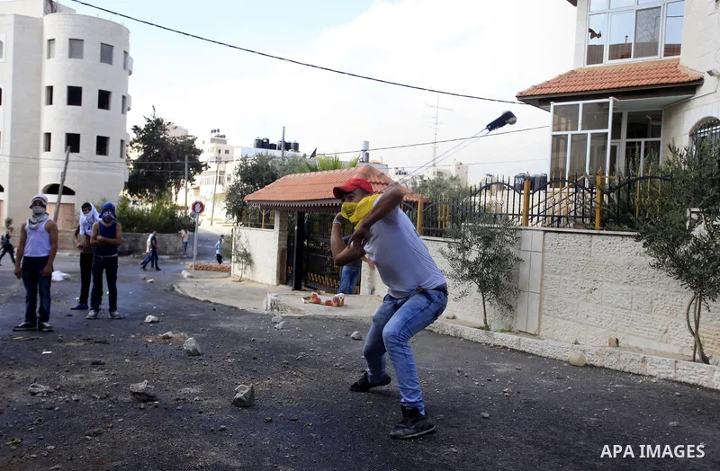 Palestinian youth throw stones towards Israeli security forces during clashes following the funeral of Eissa al-Qotri, 22, out side the Israeli settlement of Psagot, near the West Bank City of Ramallah, on Sep. 10, 2014....