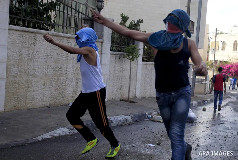 Palestinian youth throw stones towards Israeli security forces during clashes following the funeral of Eissa al-Qotri, 22, out side the Israeli settlement of Psagot, near the West Bank City of Ramallah, on Sep. 10, 2014....