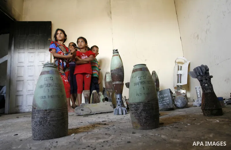 Palestinian children look at mortars and spent ammunition that, Suleiman Abu Jamaa, 35, collected around his destroyed home in Khan Yunis in the southern Gaza Strip on September 11, 2014. Israel's deputy foreign minister...