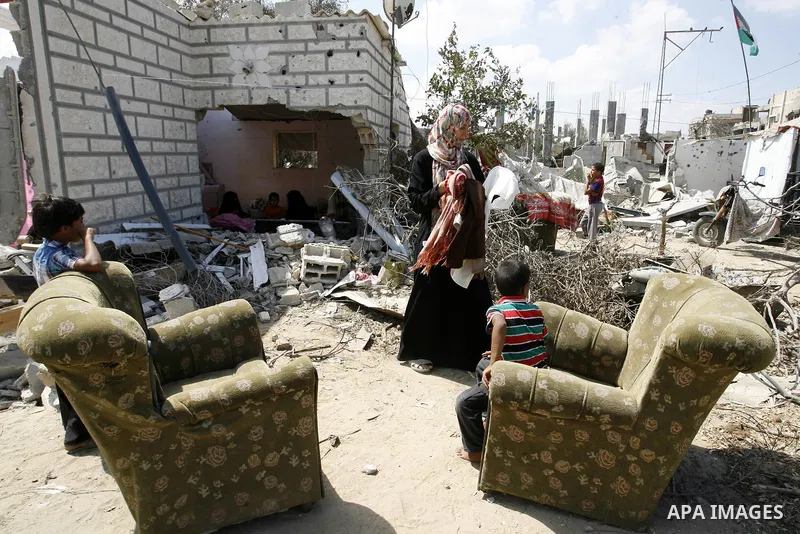 A Palestinian woman works as her sons play at their destroyed house in Khan Yunis in the southern Gaza Strip on September 11, 2014. Israel's deputy foreign minister,Tzahi Hanegbi , warned that Hamas was likely to resume...
