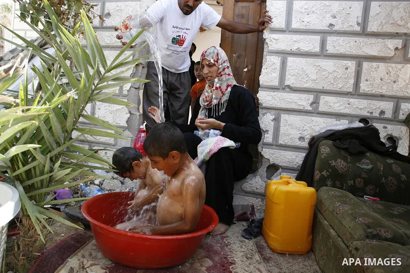 A Palestinian couple bathes their childre at a destroyed house in Khan Yunis in the southern Gaza Strip on September 11, 2014. Israel's deputy foreign minister,Tzahi Hanegbi , warned that Hamas was likely to resume "viol...