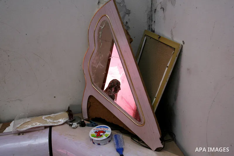 The reflection of a Palestinian woman is seen in a mirror as she prepares tea in a destroyed house in Khan Yunis in the southern Gaza Strip on September 11, 2014. Israel's deputy foreign minister,Tzahi Hanegbi , warned t...