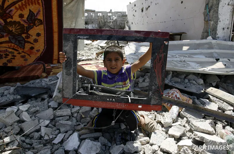A Palestinian boy holds a damaged television on the rubble of a destroyed house in Khan Yunis in the southern Gaza Strip on September 11, 2014. Israel's deputy foreign minister,Tzahi Hanegbi , warned that Hamas was likel...