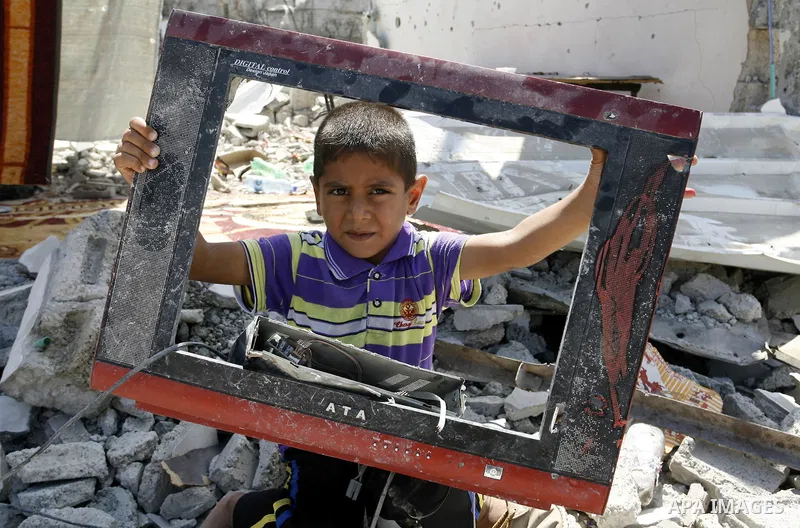 A Palestinian boy holds a damaged television on the rubble of a destroyed house in Khan Yunis in the southern Gaza Strip on September 11, 2014. Israel's deputy foreign minister,Tzahi Hanegbi , warned that Hamas was likel...