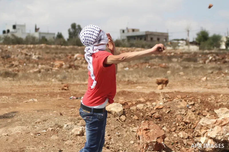A Palestinian protester uses a sling shot to hurl a stone at Israeli troops during clashes at a weekly protest against Jewish settlements, in the West Bank village of Nabi Saleh, near Ramallah, September 12, 2014. Photo...