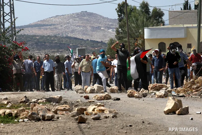 Palestinian protesters throw stones towards an Israeli security forces during clashes following a protest in the village of Kfar Qaddum, near the northern city of Nablus, in the occupied West Bank on September 12, 2014....