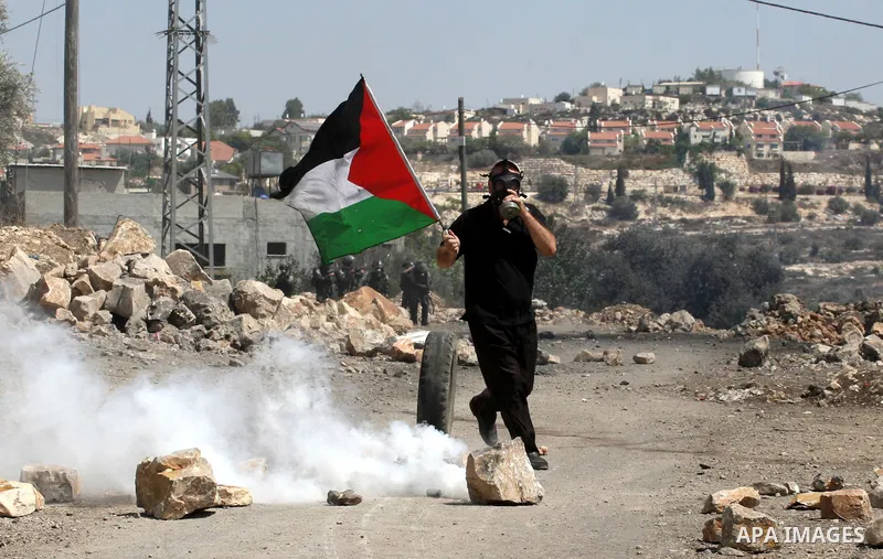 A Palestinian protester waves a national flag during clashes with Israeli security forces following a protest in the village of Kfar Qaddum, near the northern city of Nablus, in the occupied West Bank on September 12, 20...