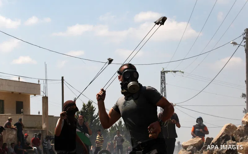 A Palestinian protester uses a slingshot to throw stones towards an Israeli security forces during clashes following a protest in the village of Kfar Qaddum, near the northern city of Nablus, in the occupied West Bank on...