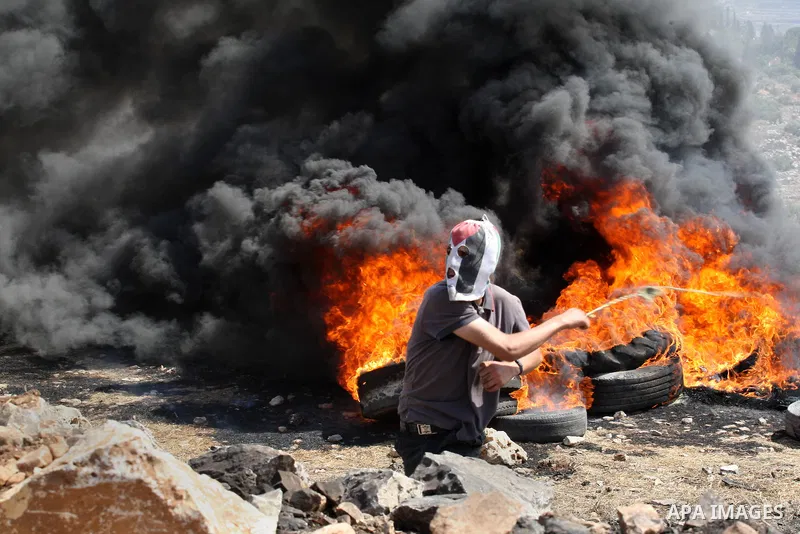 A Palestinian protester uses a slingshot to throw stones towards an Israeli security forces during clashes following a protest in the village of Kfar Qaddum, near the northern city of Nablus, in the occupied West Bank on...