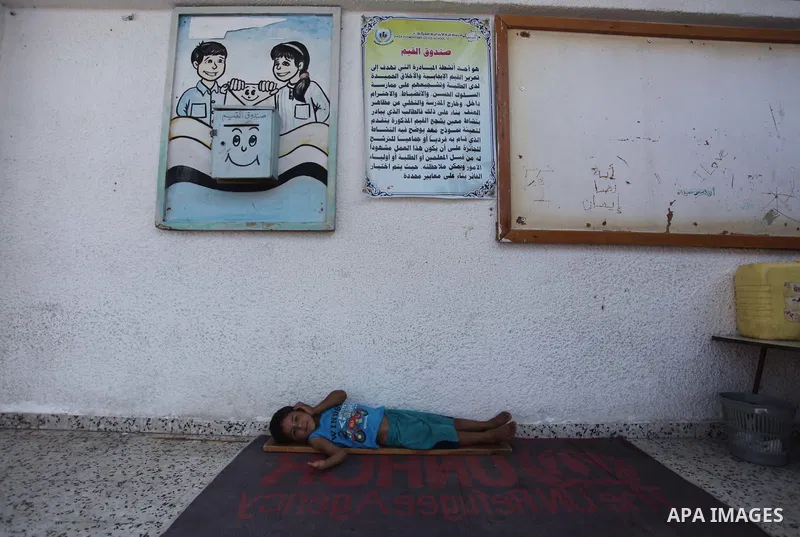 A displaced Palestinian boy sleeps at class in a United Nations-run school, in Gaza city, on Sept. 13, 2014. Some 34 school buildings in Gaza are damaged beyond repair and 31 more are still being used as shelters, while...